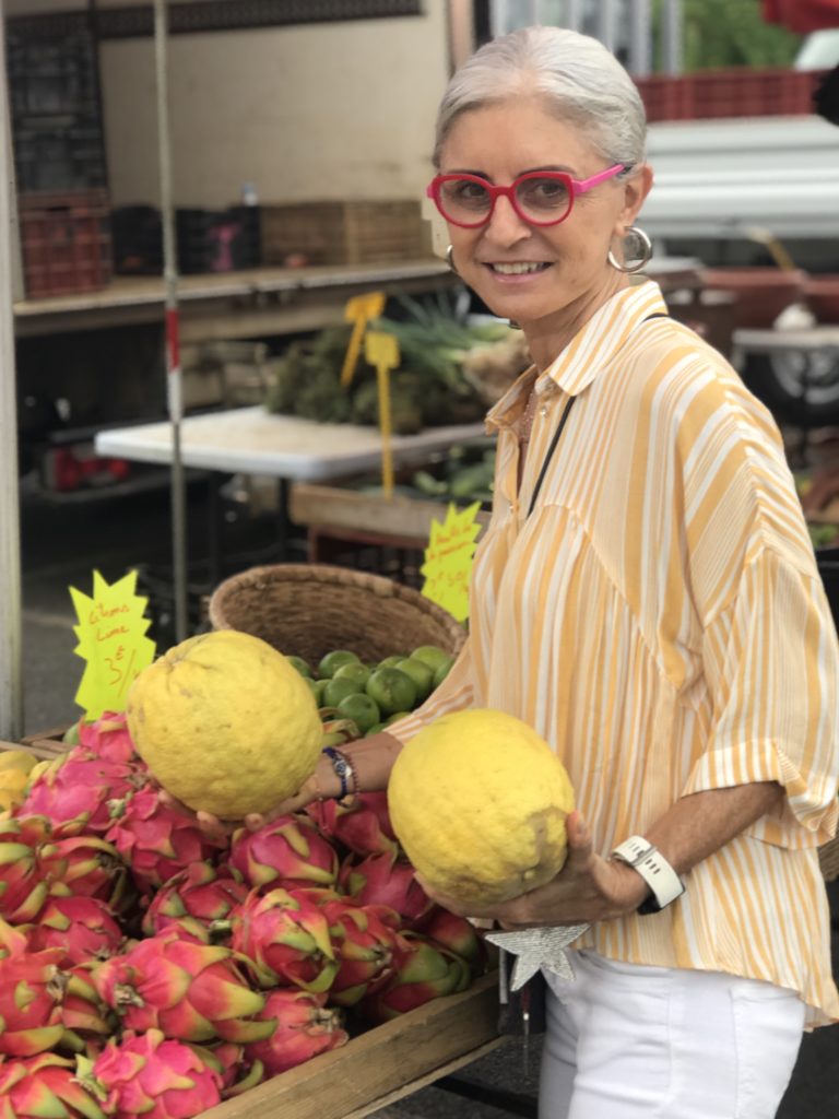 Corinne Romeder choisissant des agrumes au marché forain de Saint-Paul