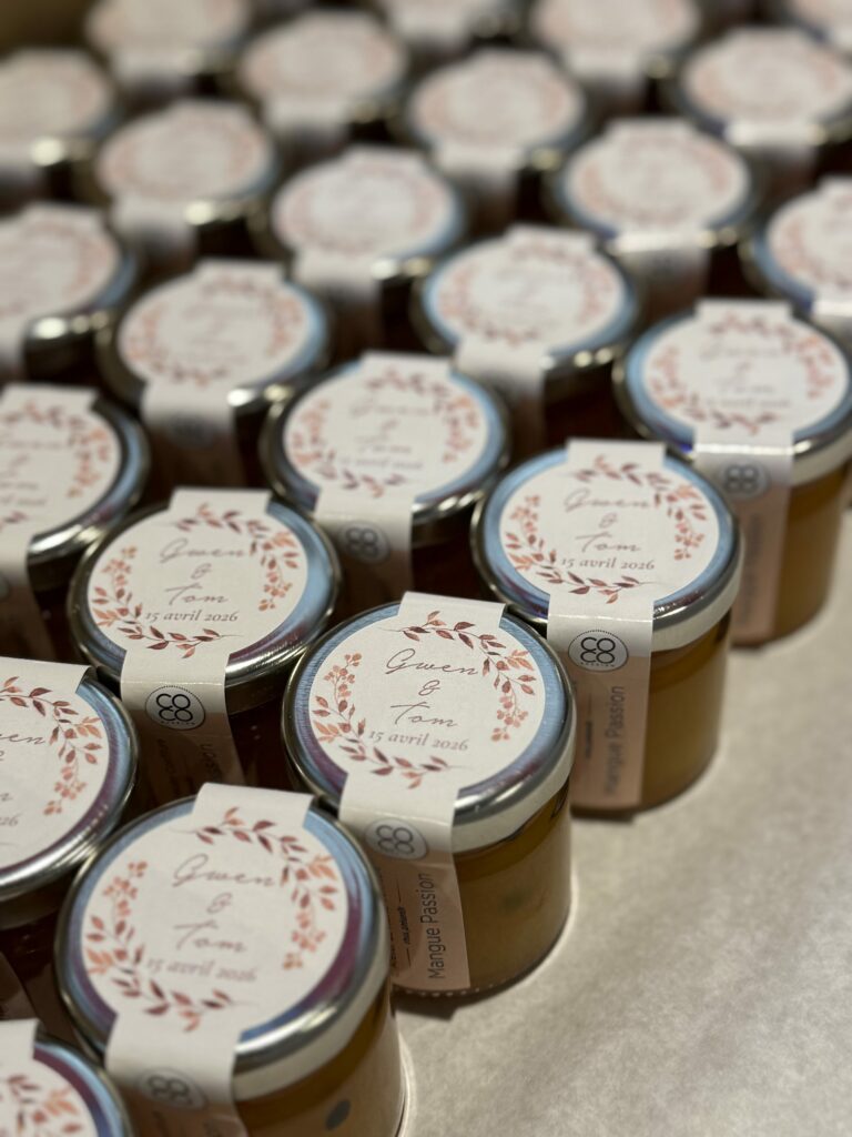 Rangées de petits pots de confiture aux étiquettes de mariage ornées d'une couronne de feuillage